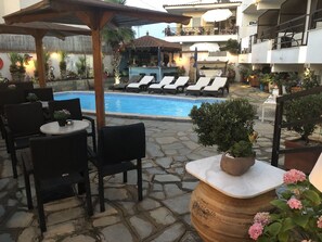 A poolside area with lounge chairs, a bar, and a stone-tiled patio.