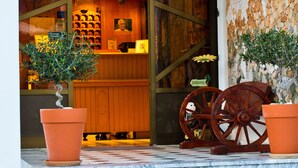 A hotel entrance with a marble staircase, a wooden reception desk, and two potted plants.