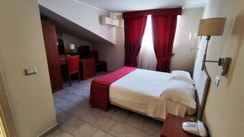A hotel room with a bed, desk, chair, and a telephone.