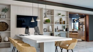 Una cocina moderna con una isla central, iluminación colgante y estanterías empotradas.