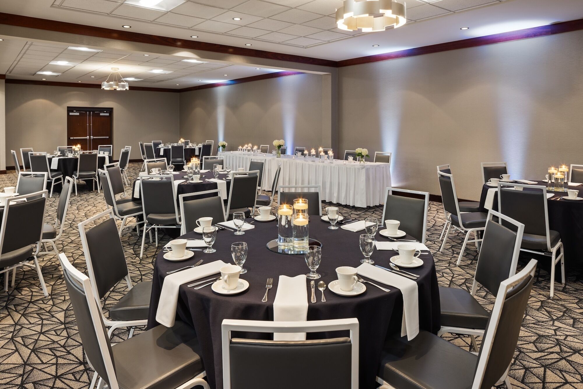 A conference room with round tables, black and white chairs, and a carpeted floor.