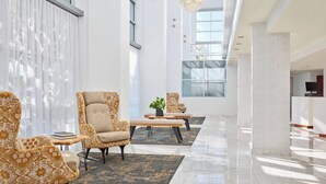 Un vestíbulo espacioso con muebles modernos, ventanas amplias y un diseño limpio y minimalista.