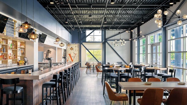 Un restaurante moderno con barra, mesas y sillas.