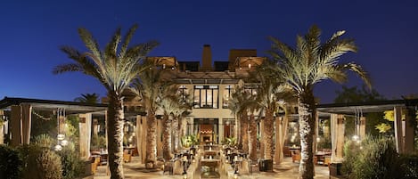 Un hotel lujoso con un patio central, palmeras y una fuente.