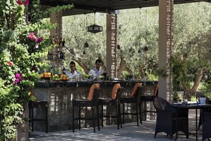 An outdoor bar area with wicker chairs and a stone counter.