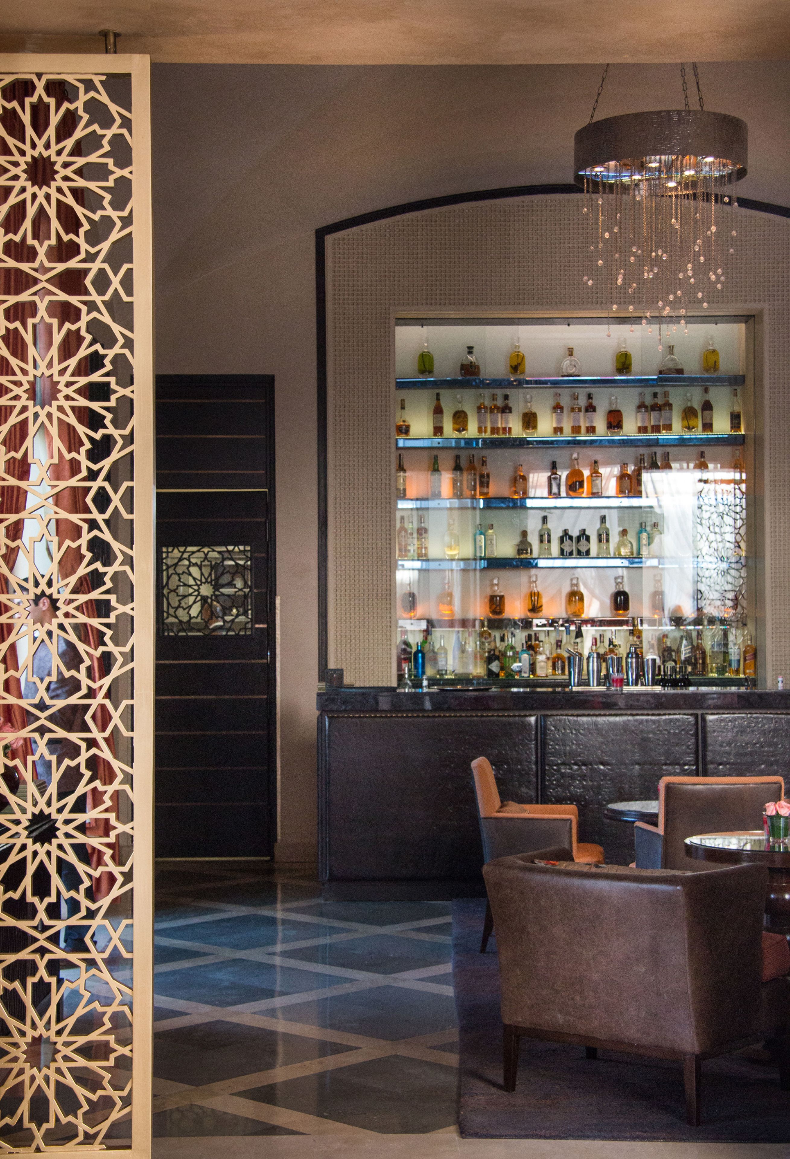 A bar area with shelves of bottles, a decorative partition, and seating.
