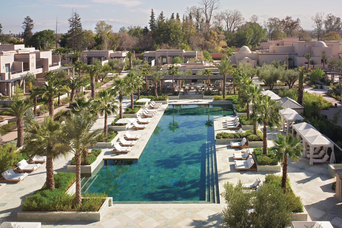 Un complexe hôtelier doté d’une longue piscine, de chaises longues et de palmiers.