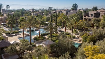 Ein Resort mit mehreren Swimmingpools, umgeben von Palmen und Liegestühlen.
