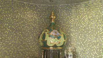 Un baño con paredes de mosaicos y una fuente decorativa.
