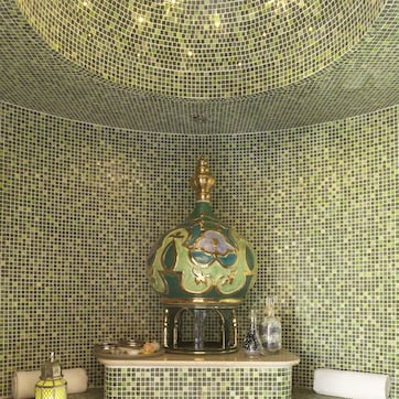 A bathroom with mosaic tile walls and a decorative fountain.