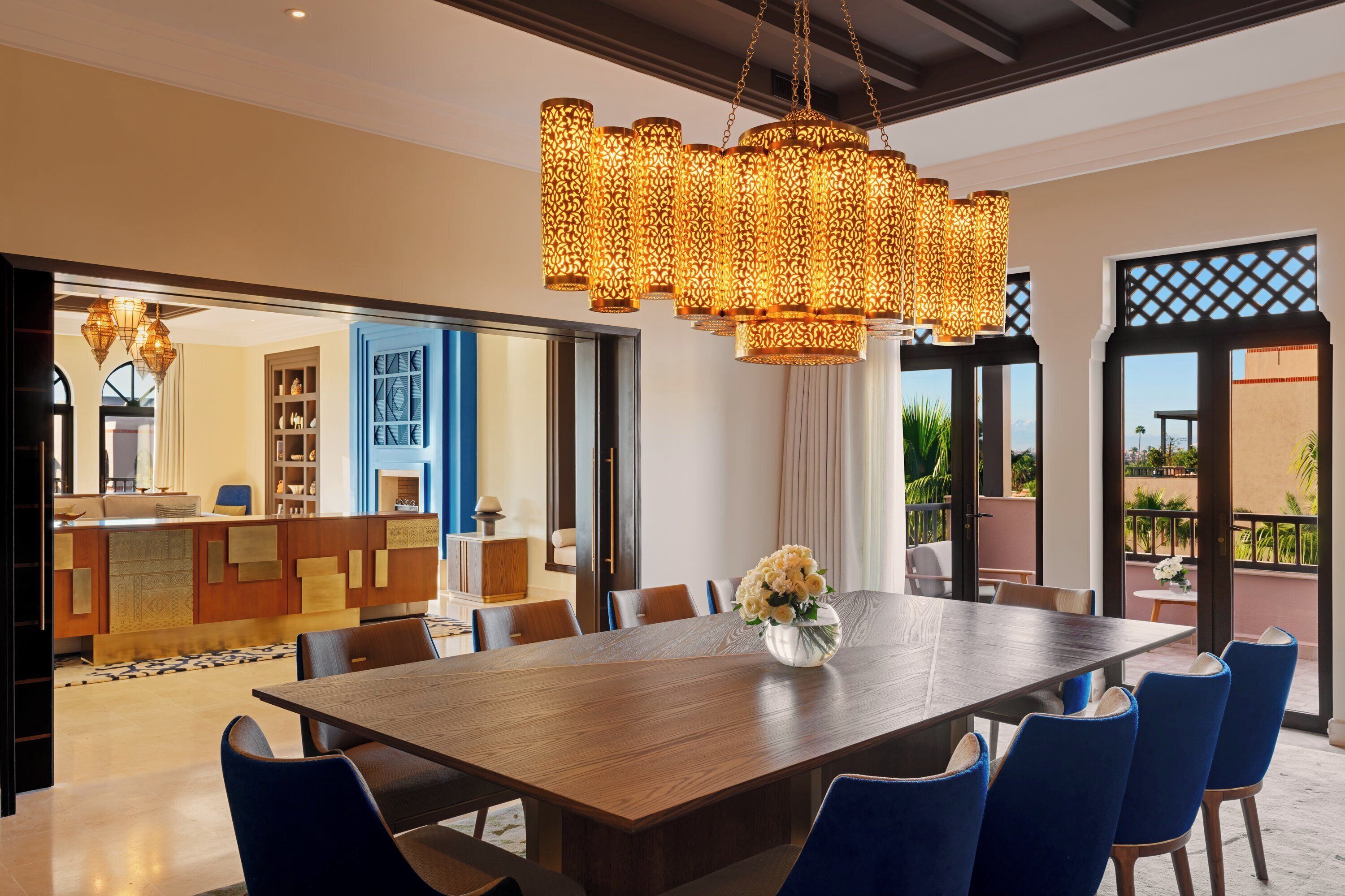 Un comedor moderno con una larga mesa de madera, sillas azules y una lámpara colgante decorativa.