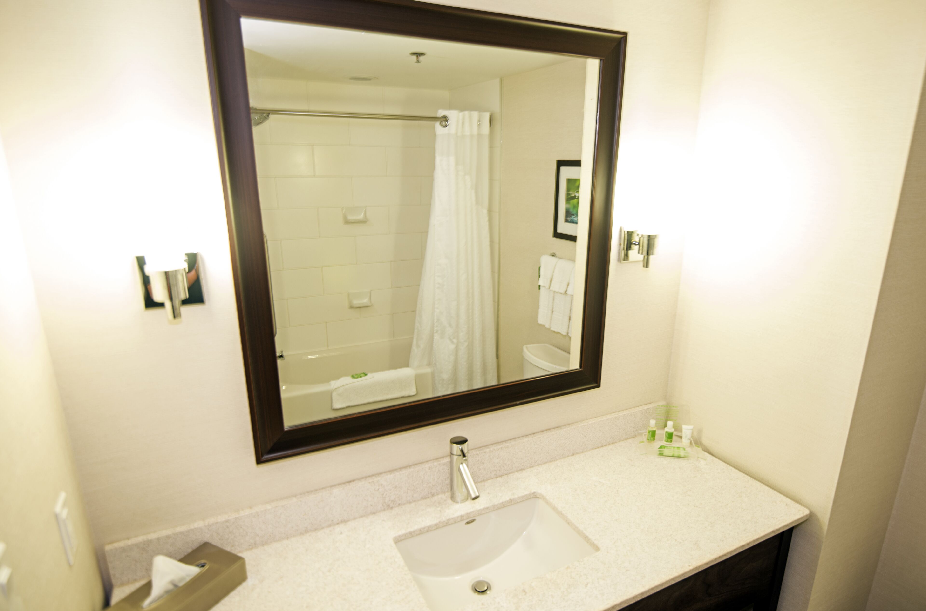Un baño con un espejo grande, un lavabo y una ducha.