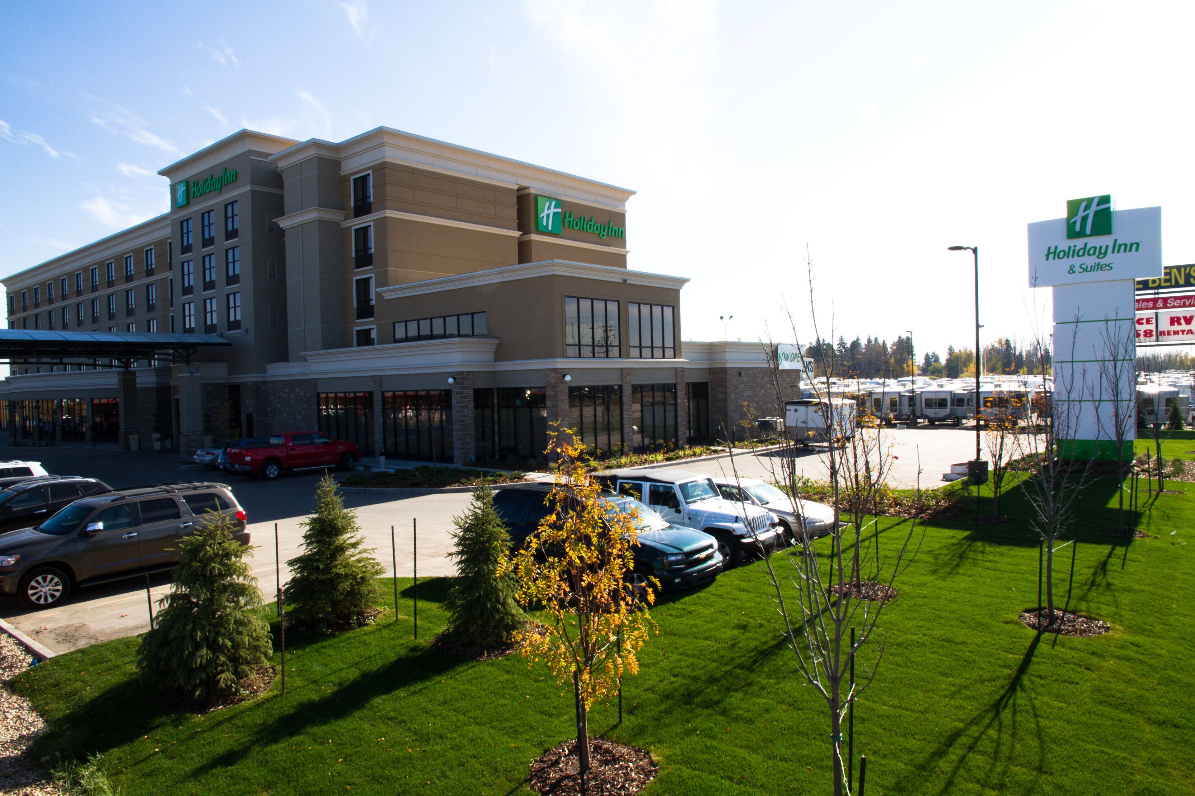 A Holiday Inn hotel with a parking lot and a green lawn area.