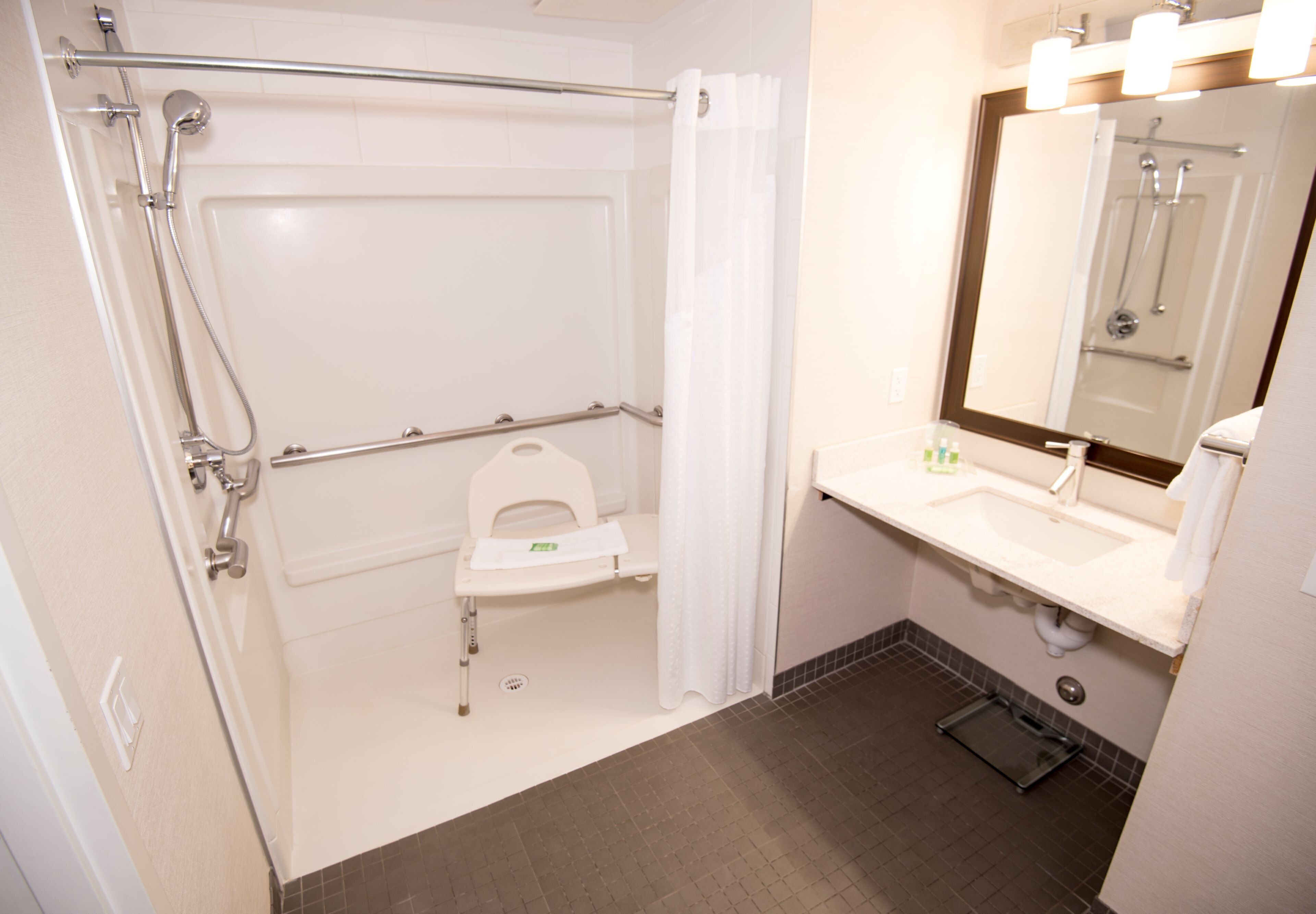 Une salle de bain avec une douche à l’italienne, des toilettes et un lavabo avec un miroir.