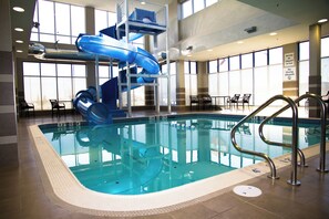 An indoor swimming pool with a blue water slide, clear pool edges, and a lifeguard station. - Holiday Inn Hotel & Suites Red Deer South by IHG (Red Deer)