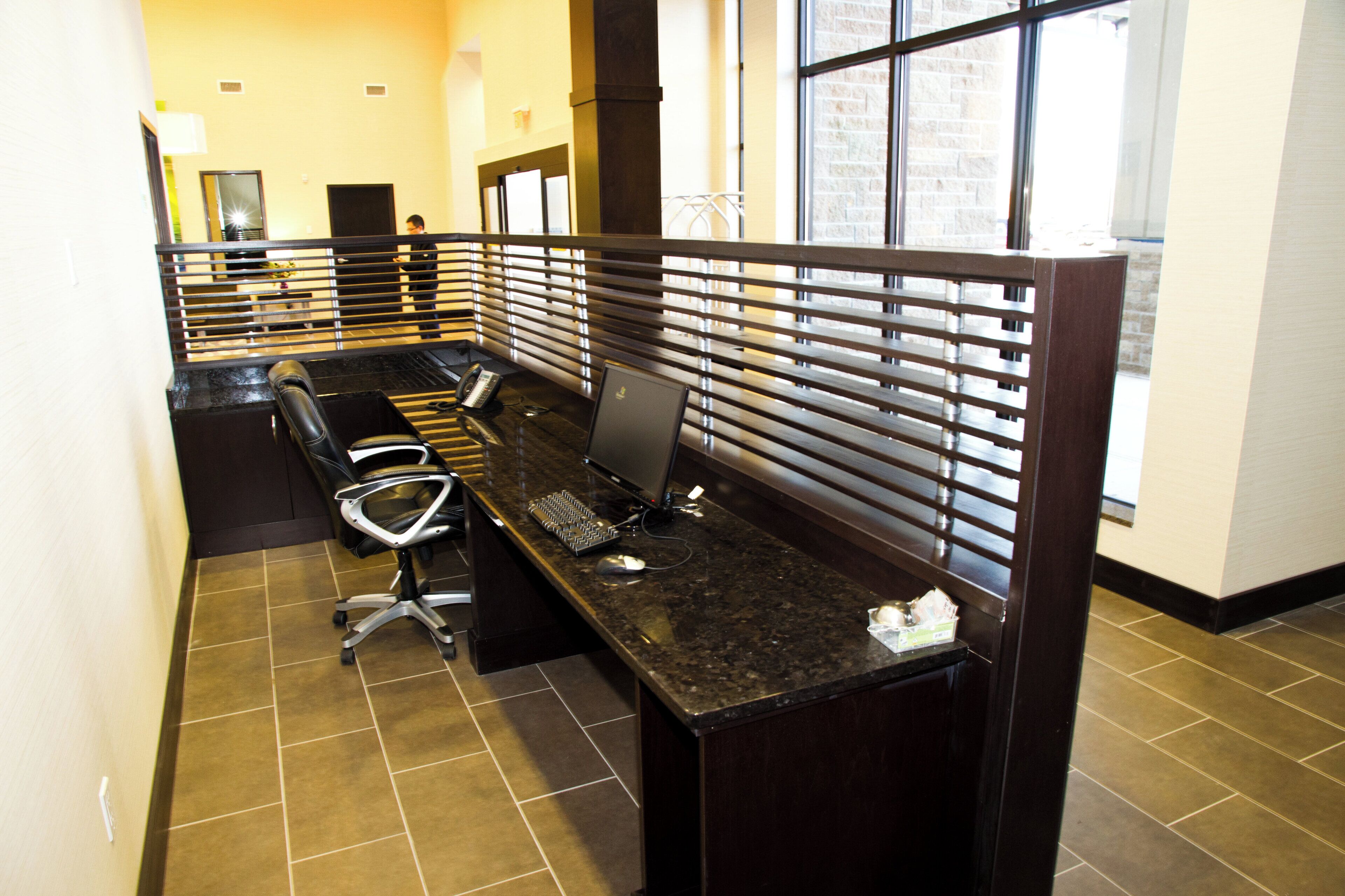 A hotel reception area with a long reception desk, individual workstations with partitions, a telephone, and a computer.