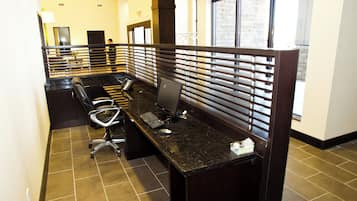 A hotel reception area with a long reception desk, individual workstations with partitions, a telephone, and a computer.