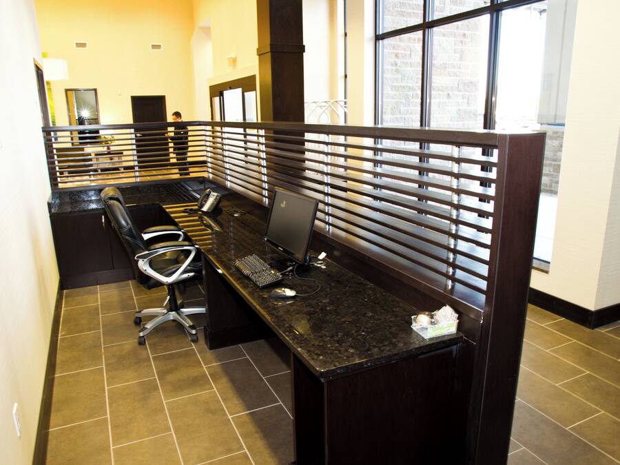 A hotel reception area with a long reception desk, individual workstations with partitions, a telephone, and a computer.