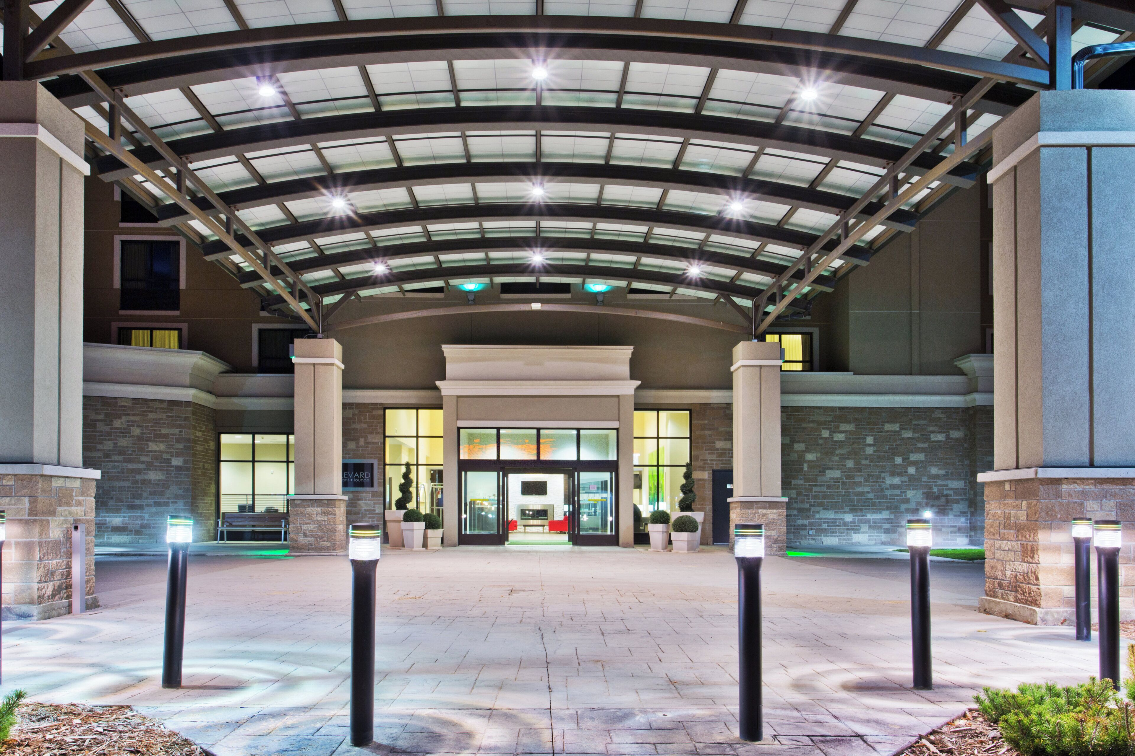 A hotel entrance with a covered walkway, a reception desk, and a visible entrance door.