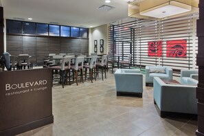 A restaurant lounge with a modern interior, featuring a reception desk, seating area with tables and chairs, and a decorative wall with a rose pattern. - Holiday Inn Hotel & Suites Red Deer South by IHG (Red Deer)