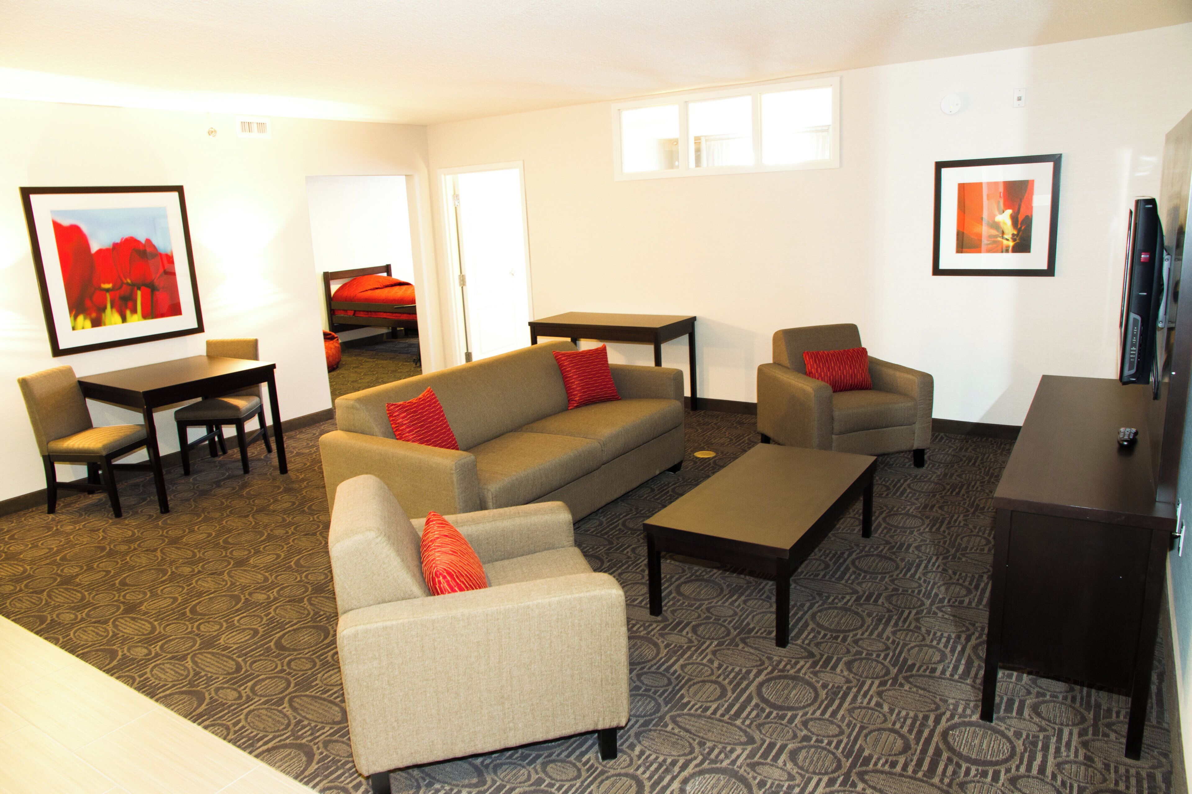 A furnished living room with a sofa, armchairs, a coffee table, and a TV stand.
