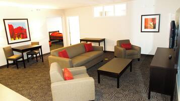A furnished living room with a sofa, armchairs, a coffee table, and a TV stand.