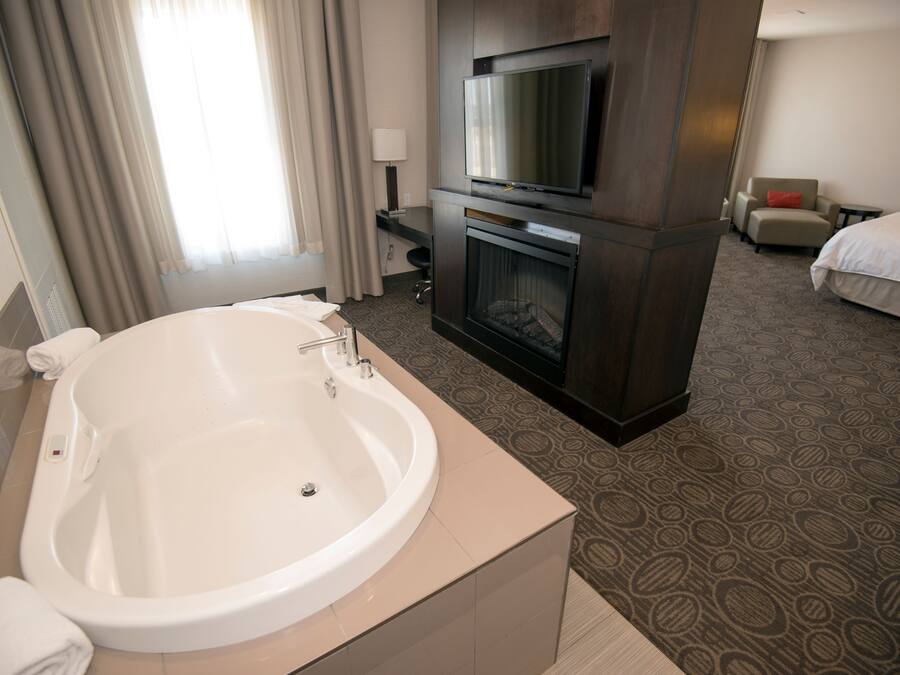 Una habitación de hotel con una bañera grande, televisor, chimenea y cama.