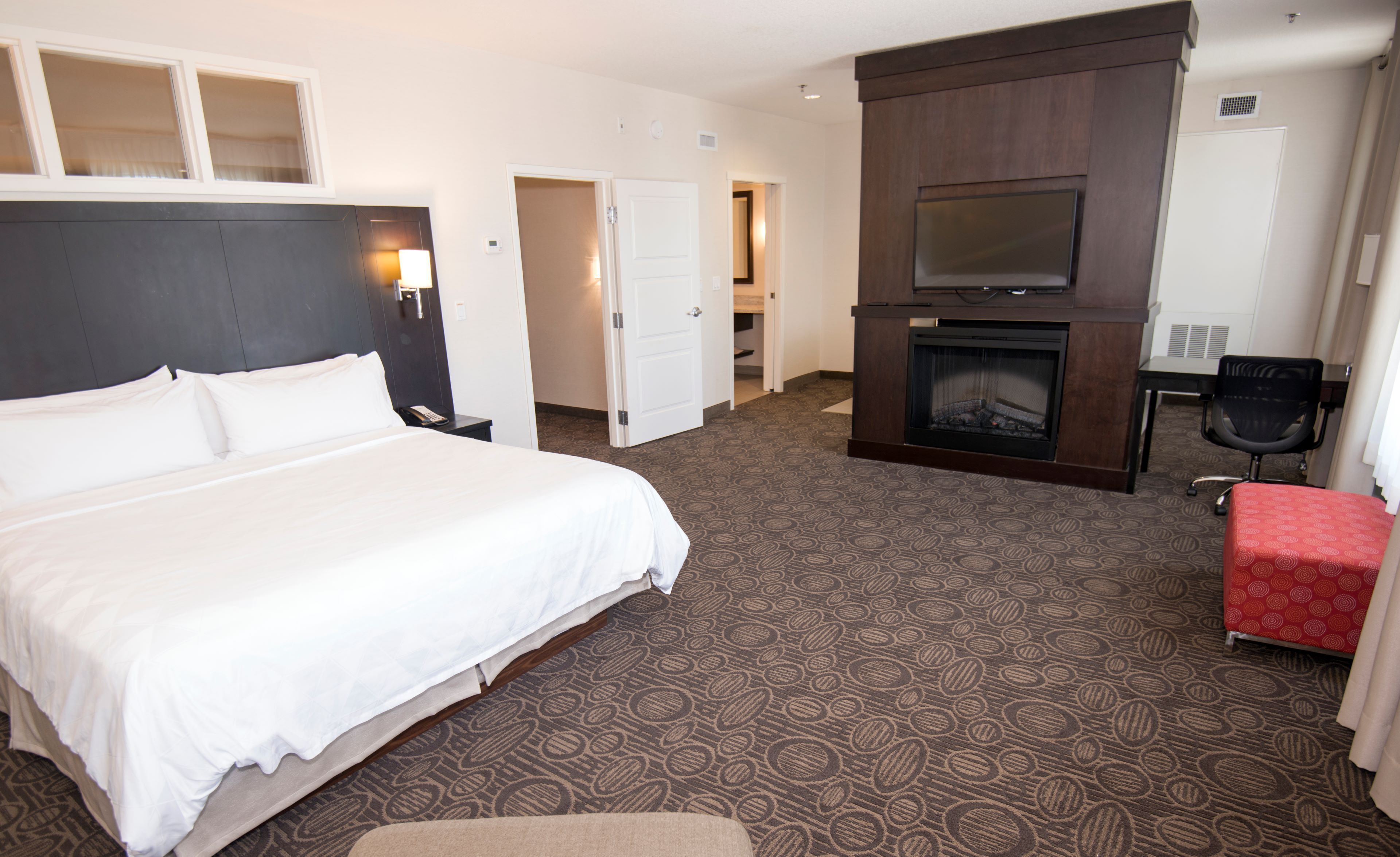 Une chambre d’hôtel avec un grand lit, une télévision, une cheminée et un bureau.