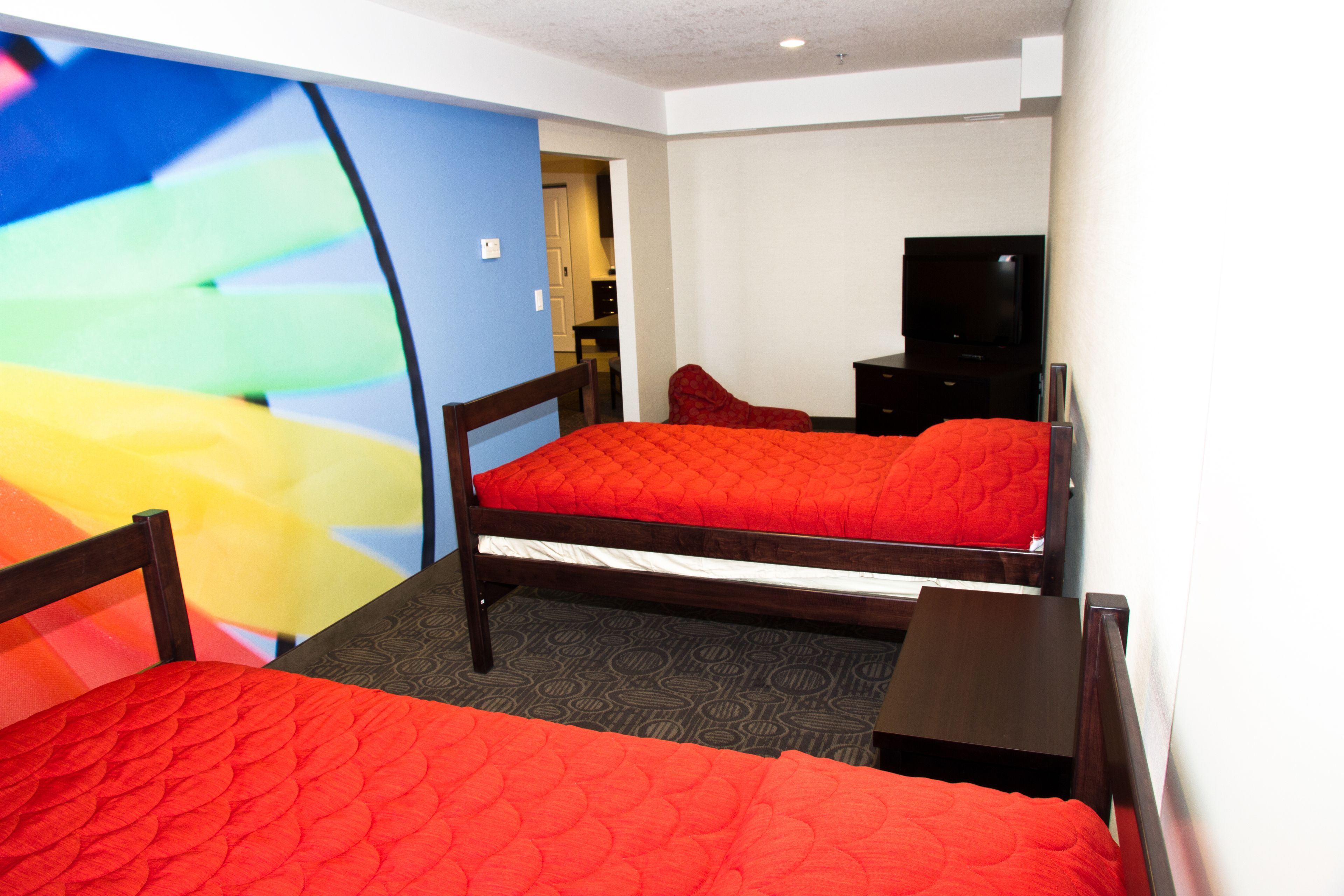 A hotel room with two beds, a TV, and a desk.