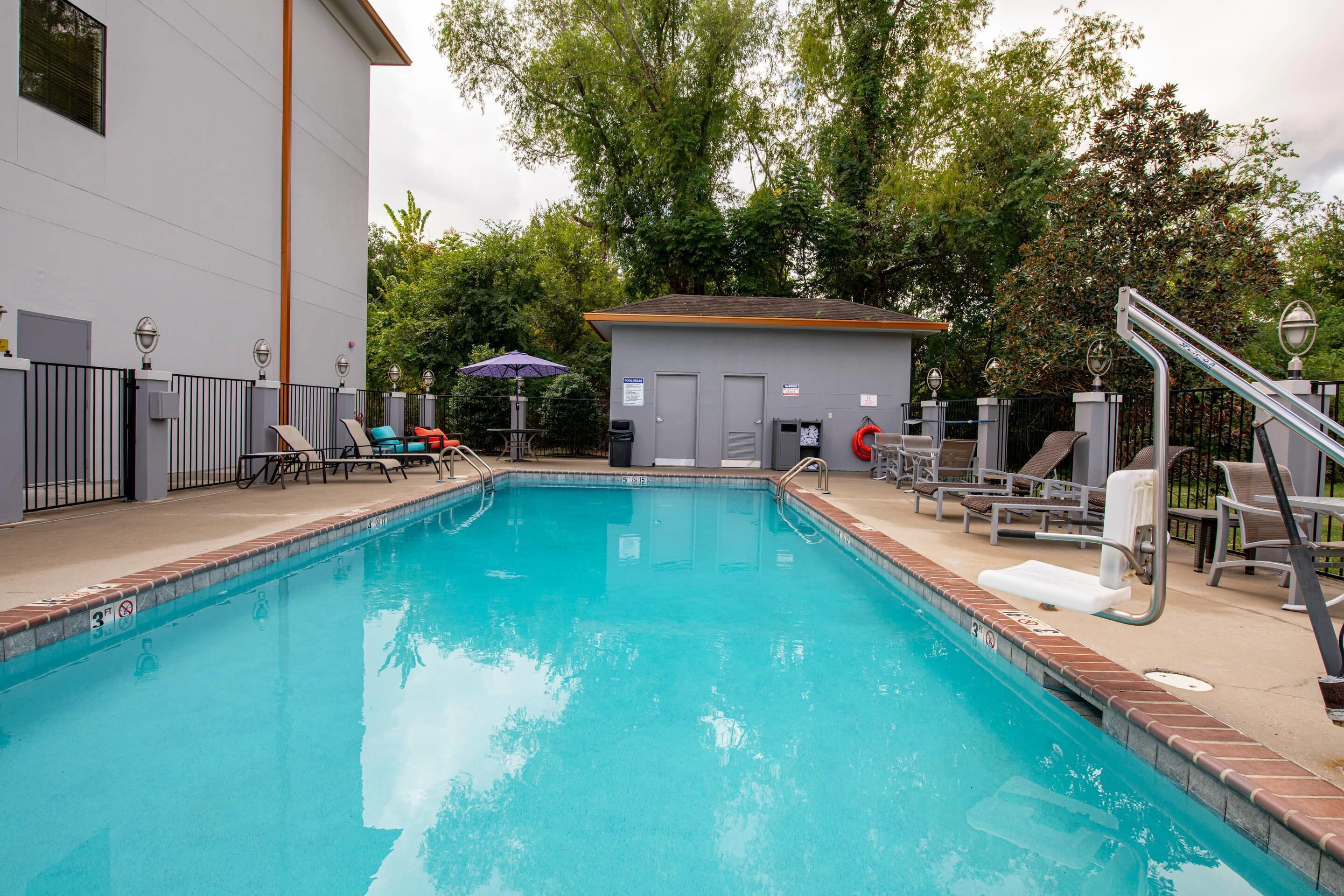 A swimming pool with lounge chairs and a small building in the background.