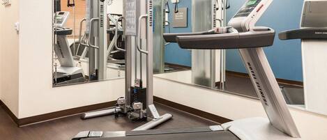 A hotel fitness center with cardio machines, free weights, and a treadmill.