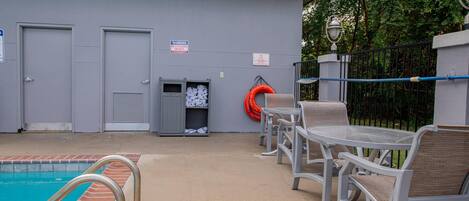 Zona de piscina con escalera metálica, mesa de billar y mobiliario exterior.