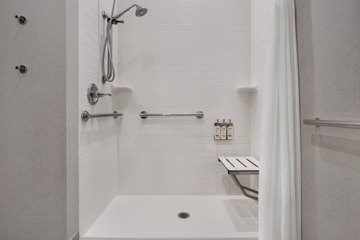 A modern shower with a handheld showerhead, a handheld shower attachment, and a handheld scrubber.