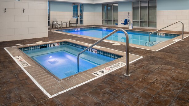 Zona de piscina de hotel con dos piscinas, cada una señalizada con indicadores de profundidad y un cartel de prohibido bucear.