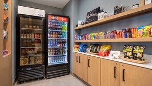 Un área de venta con dos refrigeradores llenos de refrigerios y bebidas, y estantes superiores con más refrigerios y algunas botellas.