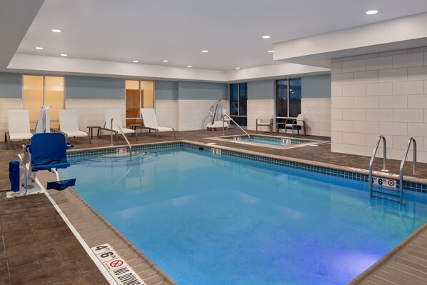 A modern indoor swimming pool with clear lane markings, a changing room, and a seating area with chairs. - Holiday Inn Express & Suites Terre Haute by IHG (Terre Haute)