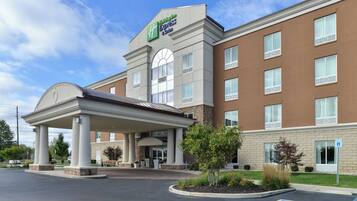 Un hotel Holiday Inn Express & Suites con entrada cubierta, múltiples ventanas y un estacionamiento que incluye señal de estacionamiento para discapacitados.