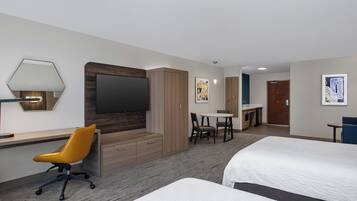A hotel room with a bed, a desk, a chair, a television, and a small table.