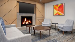 Una sala de estar moderna con chimenea, dos sillones grises, un sofá y una mesa de centro.