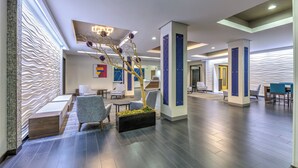A modern lobby with seating areas, a reception desk, and a decorative tree centerpiece. - Holiday Inn Express & Suites Amarillo West by IHG (Amarillo)