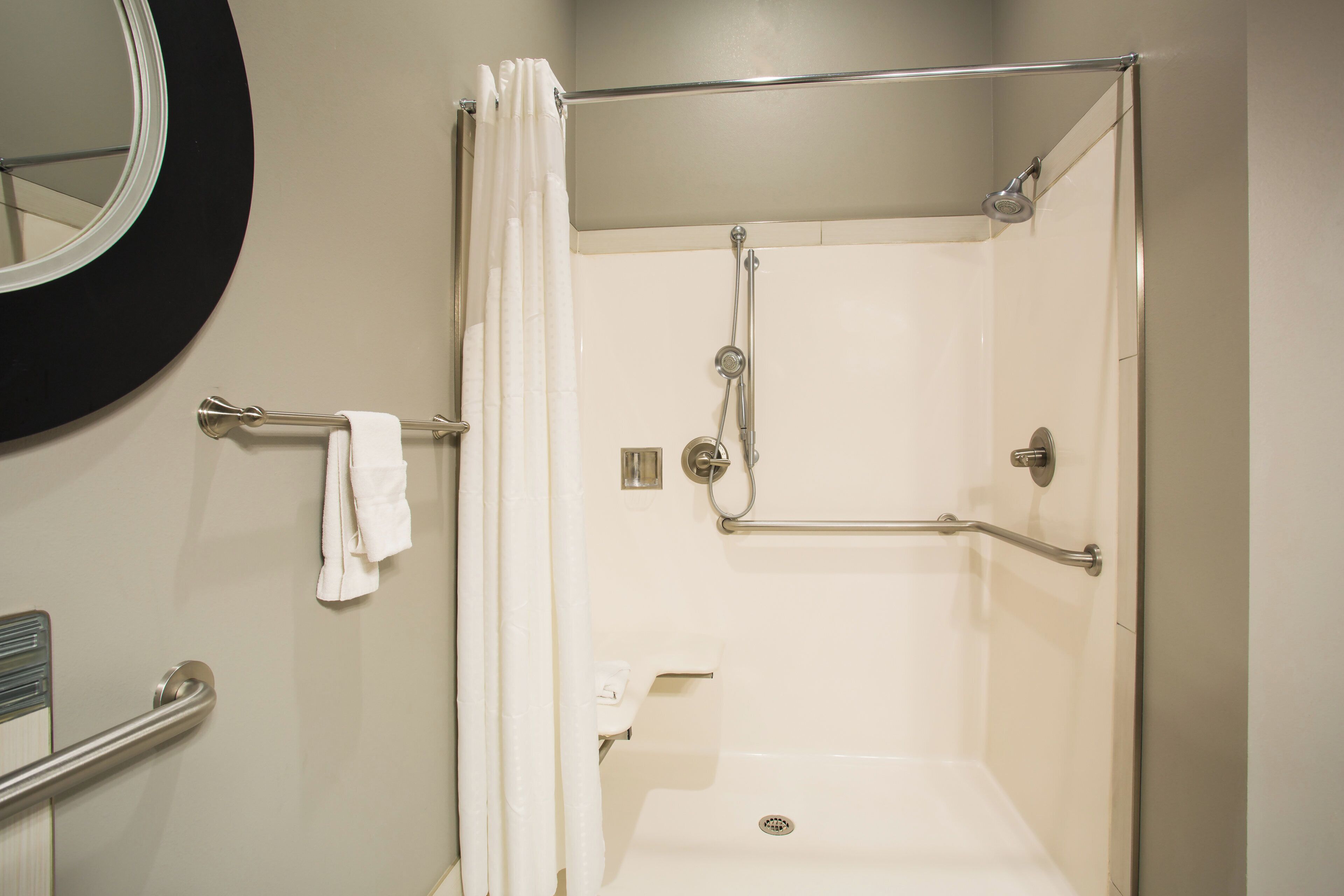 A walk-in shower with a glass door, a handrail, a towel rack, and a toilet.