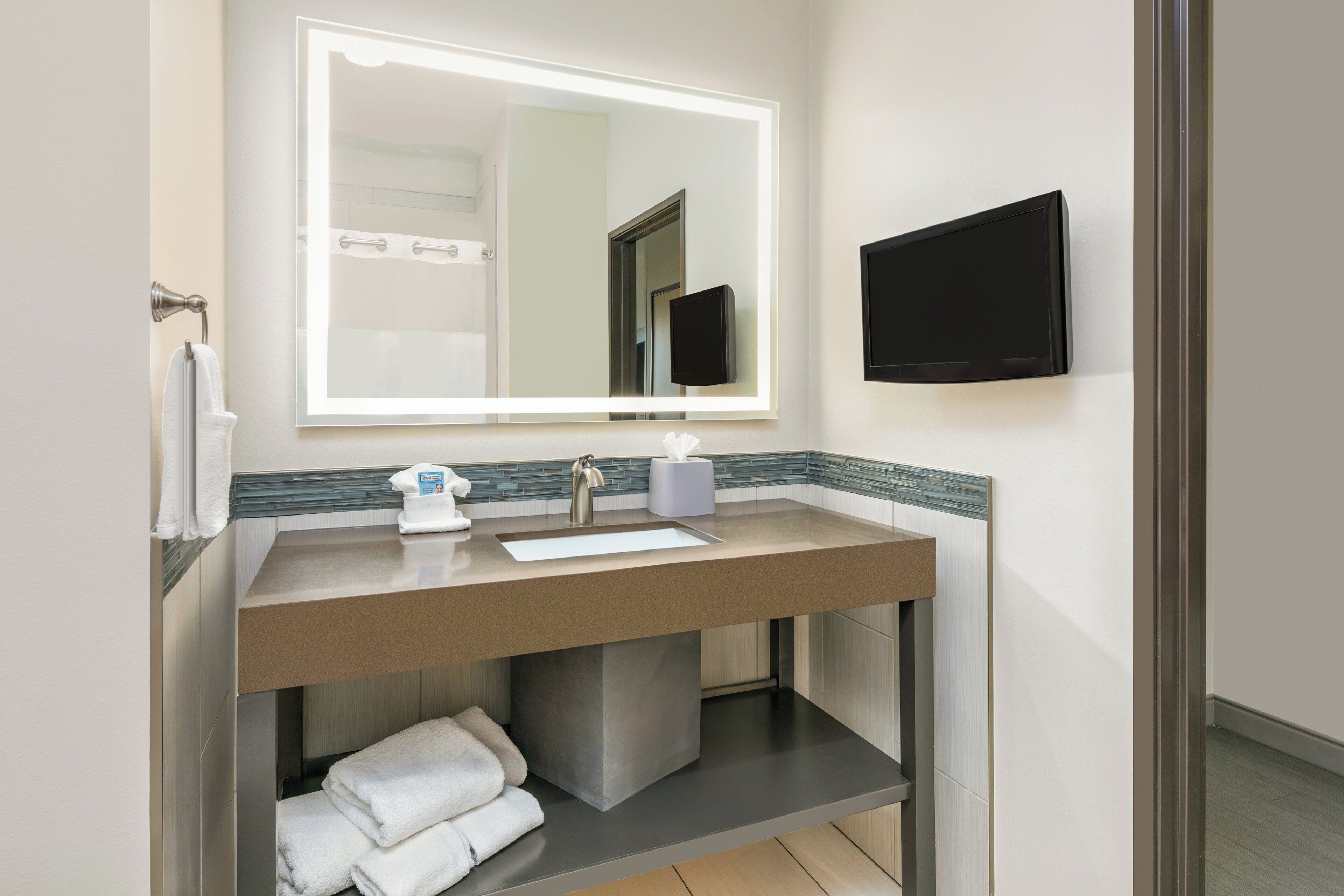A modern bathroom with a large mirror, a sink, and a toilet.