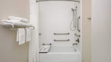 Un baño moderno con bañera, ducha y barras de apoyo.
