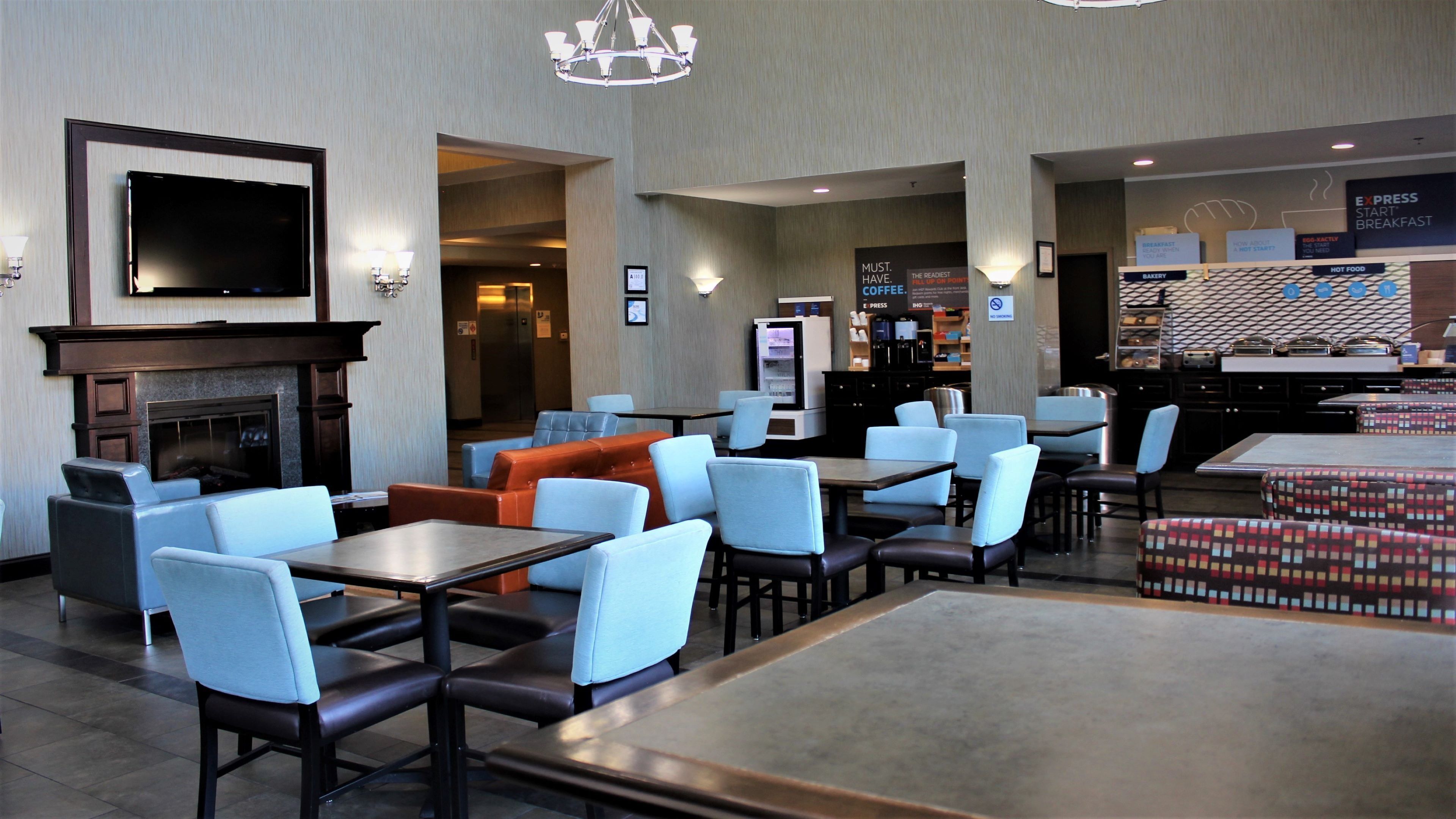 Vestíbulo de hotel con áreas de estar, chimenea, televisor y barra de desayuno.