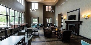A spacious dining area with high ceilings, large windows, and a fireplace.