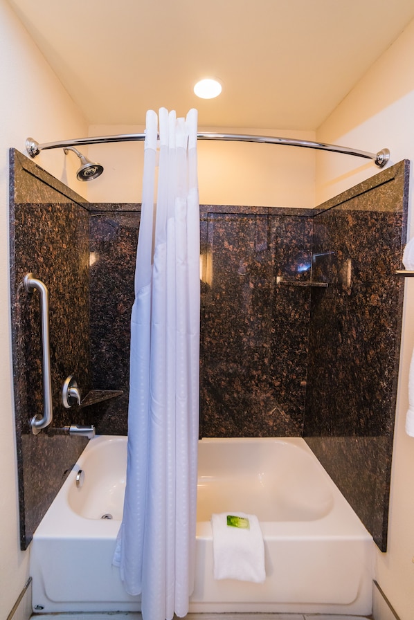 A modern bathroom with a bathtub, a shower, and a handrail.