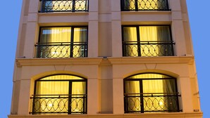 A multi-story hotel with large arched windows and balconies, featuring a well-lit entrance and potted plants at the base. - Perula Hotel & SPA (Istanbul)