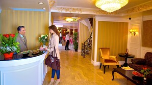 A hotel reception area with a reception desk, a chandelier, and a staircase leading to another floor. - Perula Hotel & SPA (Istanbul)
