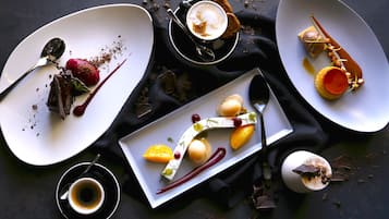 A dessert table with various plated desserts and a cup of coffee.