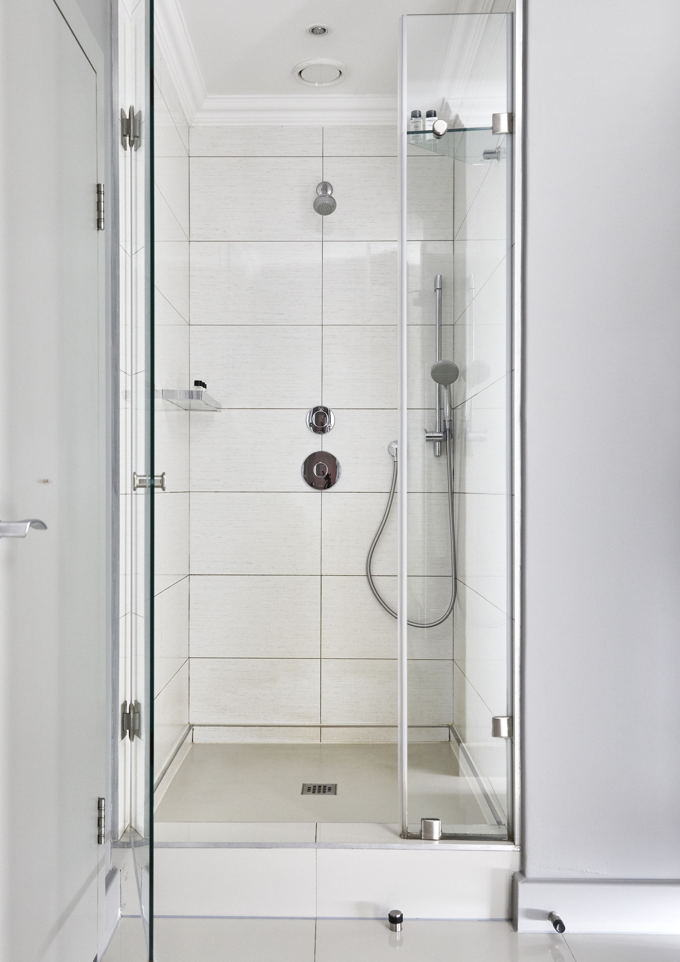 A modern shower with a glass enclosure, a handheld showerhead, and a wall-mounted faucet.